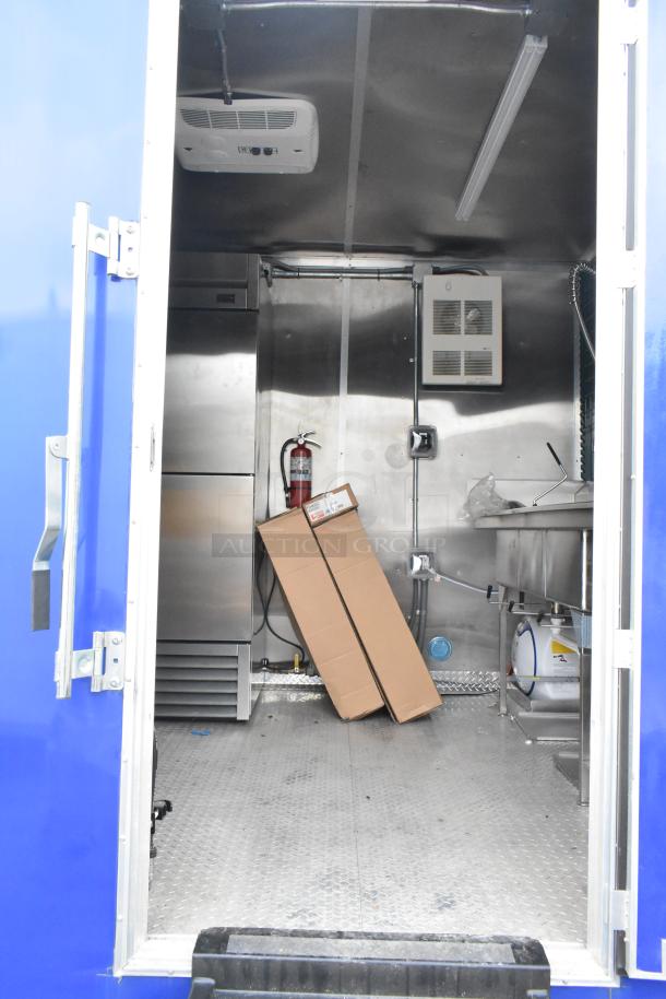 Brand new 2021 food trailer interior with CaptiveAire grease hood, True freezers, cooler, sink, and various kitchen fixtures.
