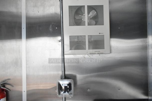 Stainless steel interior of a new food trailer with a wall-mounted electrical panel and visible fire extinguisher.