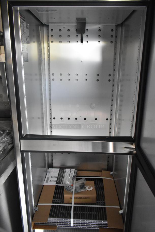Food trailer interior view with a CaptiveAire grease hood and three True freezers. Tags and manuals visible, new condition.