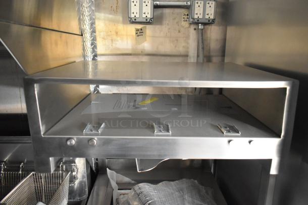 Brand new 2021 food trailer interior featuring a CaptiveAire grease hood, stainless steel surfaces, and electrical outlets.