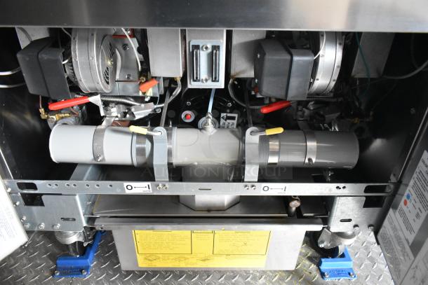 Interior view of a fully outfitted food trailer's machinery, featuring a CaptiveAire grease hood system and various piping components.