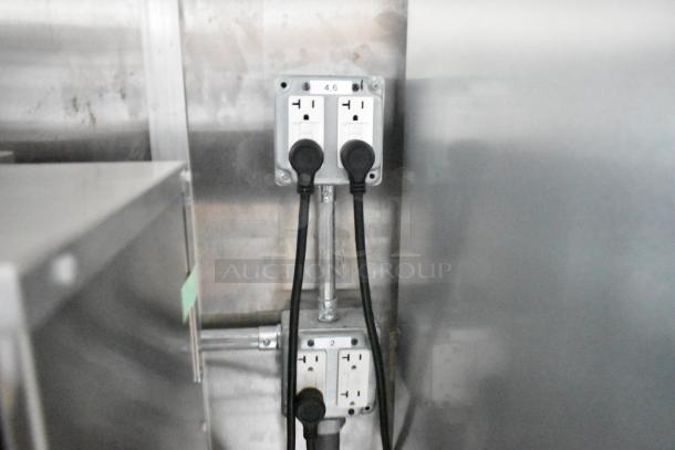 Electrical outlets with multiple power cables in a food trailer setup, stainless steel background.