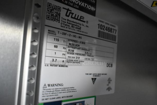 Label inside food trailer showing True refrigeration model T-23F-2-HC-MC specifications, including voltage, refrigerant type, and pressures.