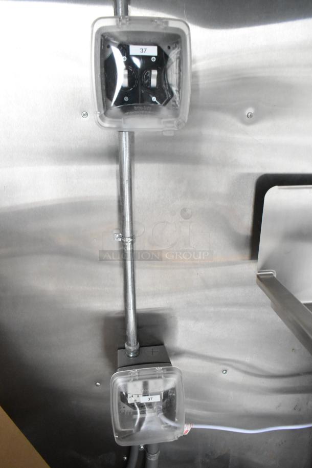 Electrical outlets with protective covers on a stainless steel wall inside a new 2021 food trailer kitchen.