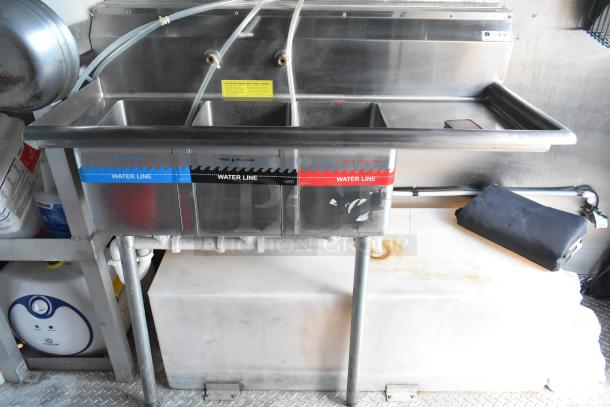 Three-compartment sink in mobile kitchen with water lines labeled. Stainless steel construction, commercial grade, new condition.