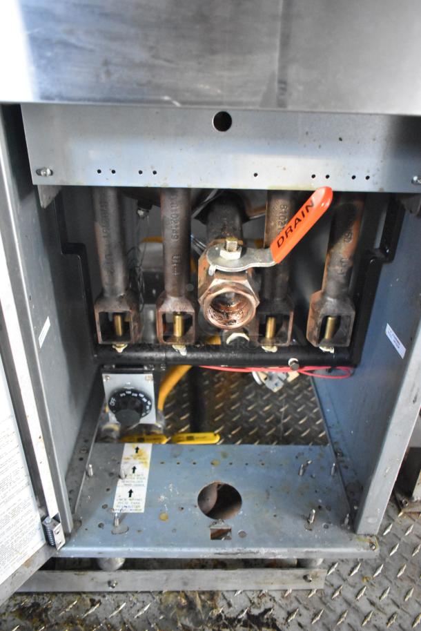 Interior view of a food trailer's gas line system, featuring four metal pipes and a red valve labeled "Drain."