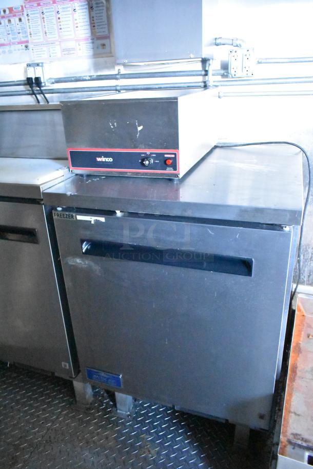 Brand new 2021 food trailer interior with Winco appliance, commercial-grade freezer, stainless steel surfaces, control panel.