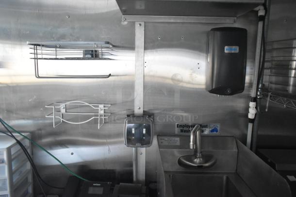 Mobile kitchen with stainless steel sink, Ecolab soap dispenser, and wire racks. Clean and fully equipped.