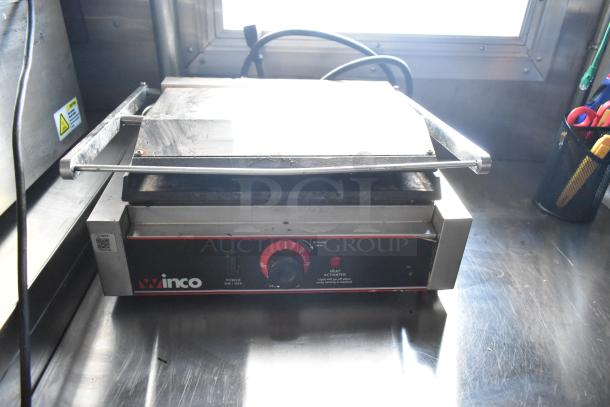 Winco commercial sandwich press on stainless steel counter, featuring heat control dial and heat indicator.