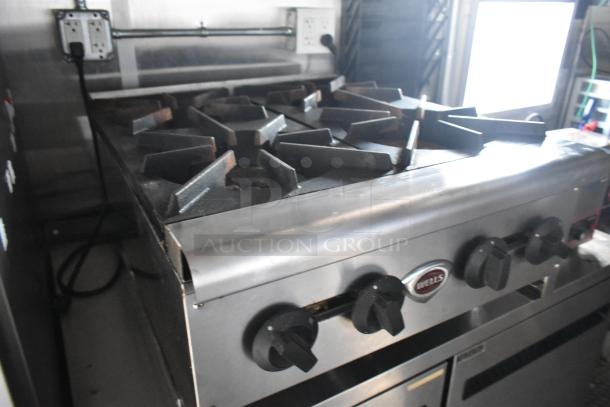 Commercial-grade stove in mobile kitchen with four burners, Wells brand, stainless steel finish, ideal for diverse food concepts.