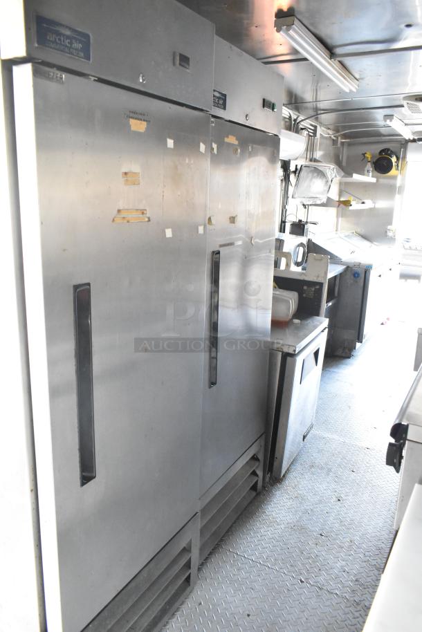Fully equipped food trailer interior featuring Arctic Air commercial coolers, stainless steel fixtures, and fire suppression system.