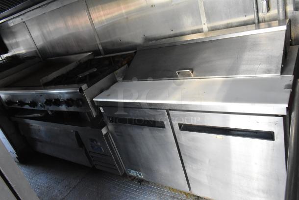 Brand new food trailer interior with commercial-grade equipment, including Wells range, Arctic Air prep table, and stainless steel surfaces.