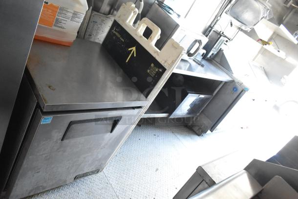 Fully equipped food trailer interior featuring Arctic Air cooler, stainless steel counters, and commercial kitchen setup.