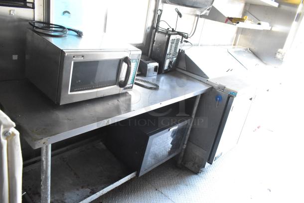 Fully equipped food trailer interior with commercial kitchen setup. Features Sharp microwave, Arctic Air prep table, and more.