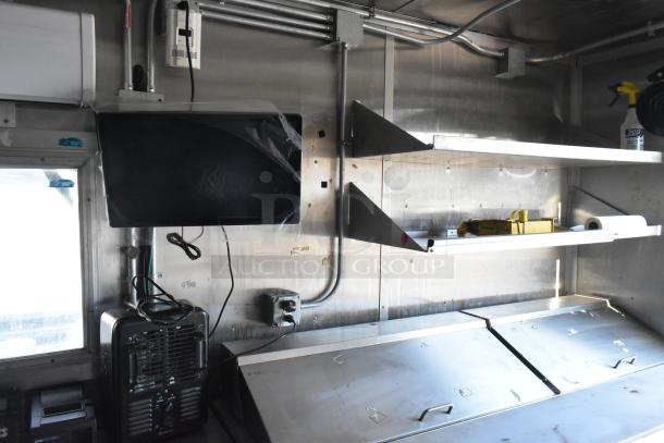 Fully outfitted food trailer interior with metal shelving, Arctic Air prep tables, and commercial-grade appliances.