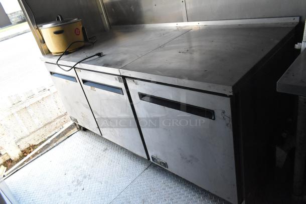 Fully outfitted food trailer interior with Arctic Air prep tables, showing stainless steel work surface and coolers.