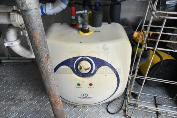 Eccotemp water heater in a food trailer, showing power and heating indicators, with pipes and rust visible on nearby metal surfaces.