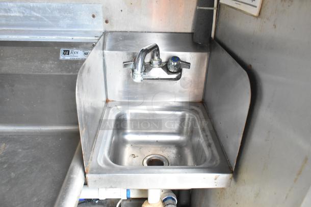 Stainless steel sink with dual-handle faucet in a commercial food trailer. NSF and Boos label visible.