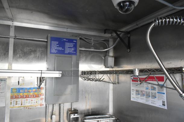 Interior of a new, fully equipped food trailer featuring a Pyrochem fire suppression system, Arctic Air appliances, and wall-mounted electrical panel with labels detailing equipment setup.