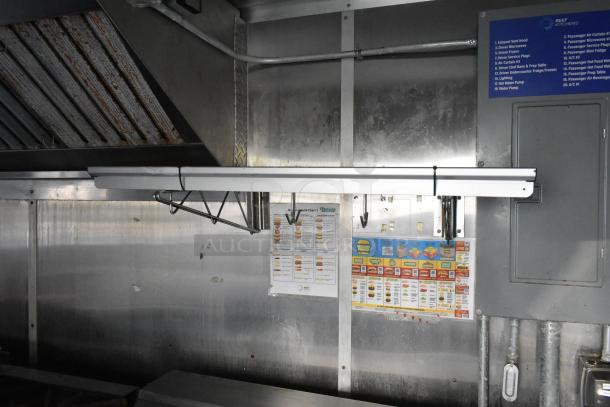 Food trailer interior with stainless steel walls, Pyrochem grease hood, and hanging hooks. Visible charts detail menu options.