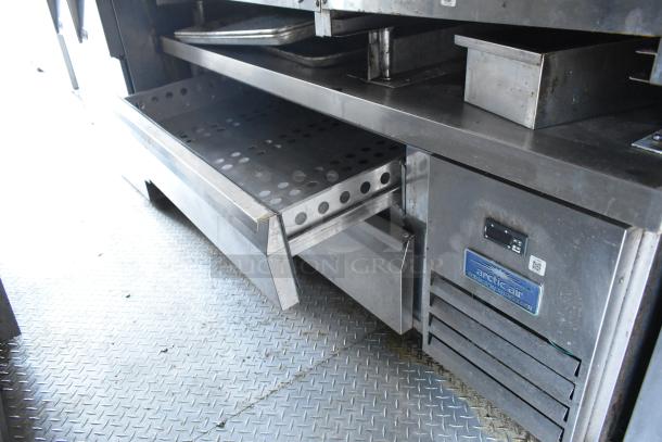 Fully equipped food trailer interior featuring Arctic Air commercial refrigerator, stainless steel prep area, and storage drawers.