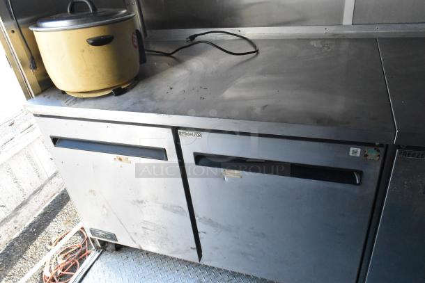 Mobile kitchen interior with Arctic Air refrigerator, freezer, and prep area. Includes rice cooker. Commercial-grade setup.