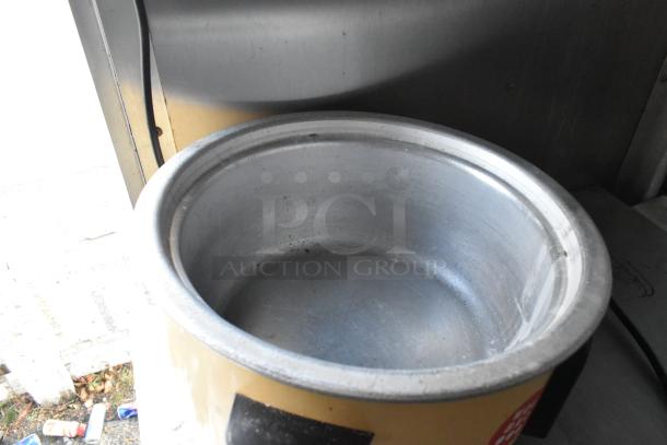 Large metal cooking pot in food trailer, featuring stainless steel interior. Visible in mobile kitchen setup.