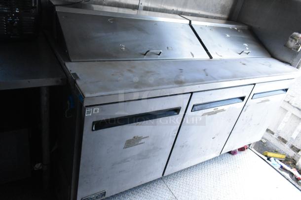Stainless steel Arctic Air prep tables in food trailer, equipped with refrigeration units, showing some surface wear.