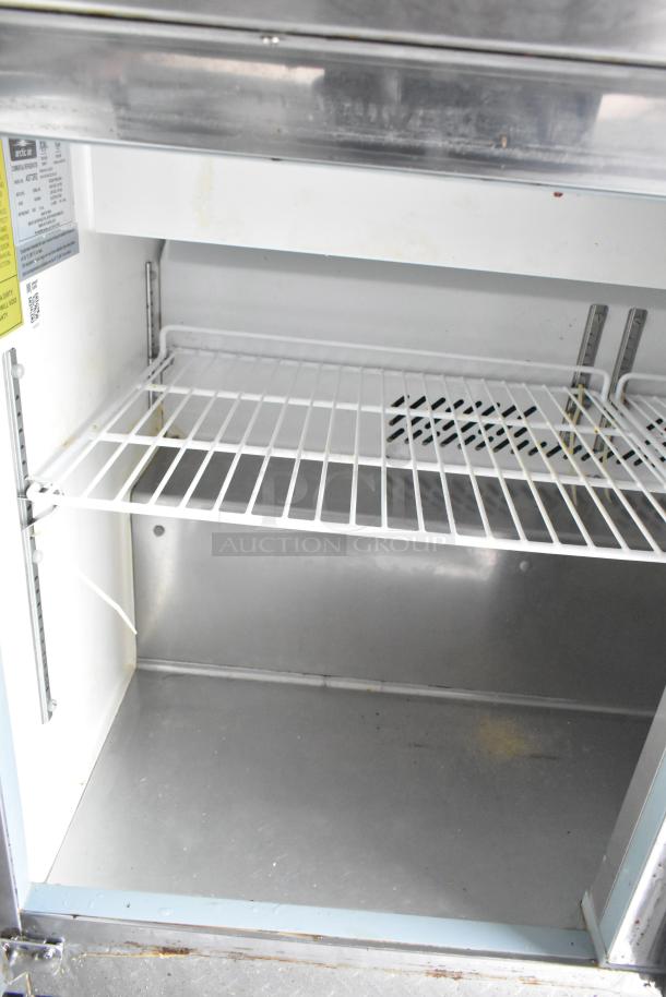 Interior of an Arctic Air Cooler in a food trailer, featuring a stainless steel shelf and interior, clean and new condition. Tags display specifications.