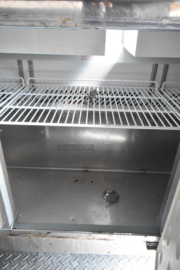 Interior view of a food trailer, showing a metal shelving unit and floor. Visible are grease marks indicating prior use.