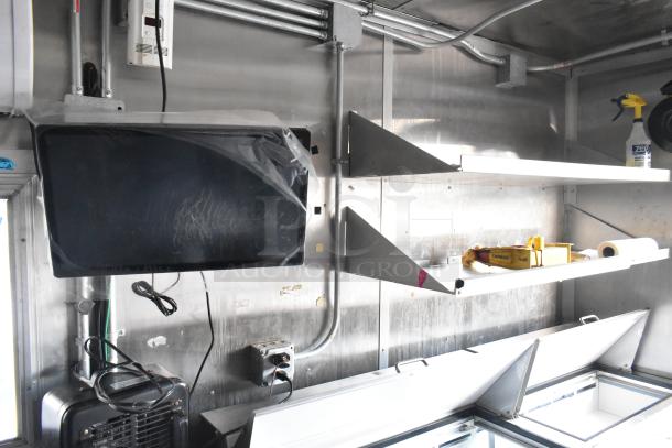 Interior of a new food trailer featuring stainless steel shelves, electrical wiring, and a commercial-grade monitor.
