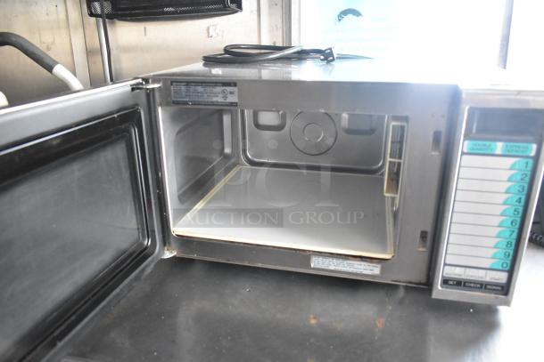 Commercial Sharp microwave in a fully equipped mobile kitchen. Features keypad and label detailing settings.
