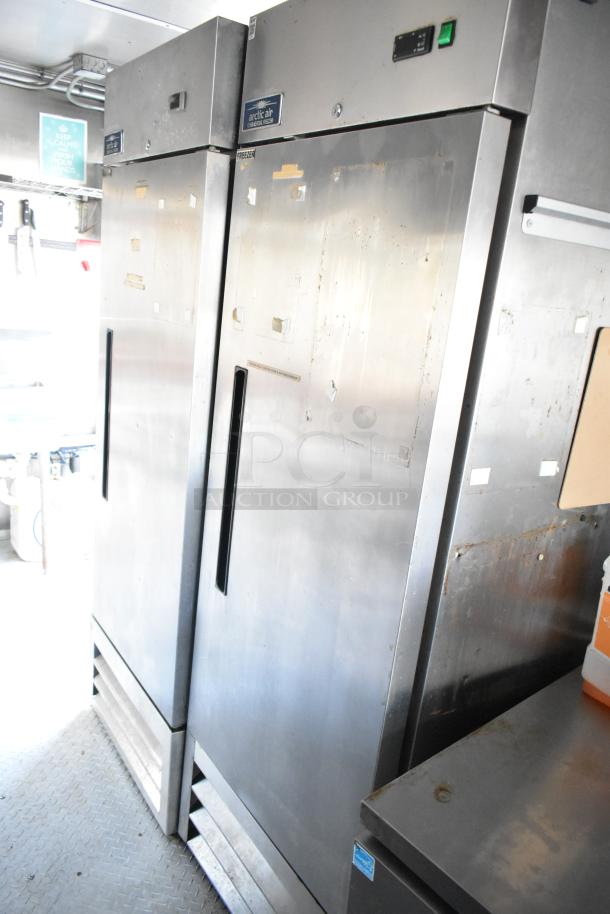 Arctic Air commercial coolers and freezer in a mobile kitchen trailer. Stainless steel, with visible handles and labels.