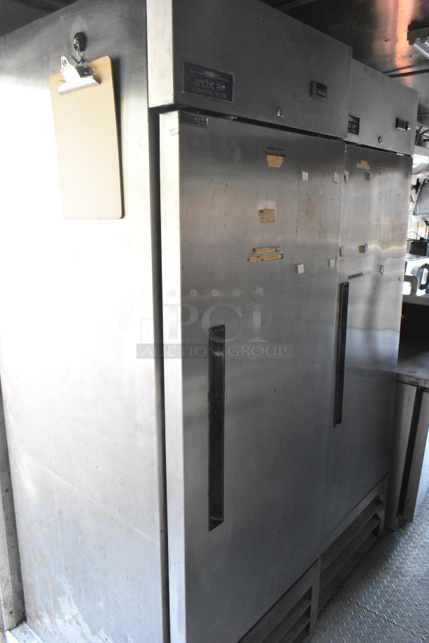 Arctic Air commercial freezers inside a fully outfitted food trailer. Shows clipboard attached. Stainless steel finish.