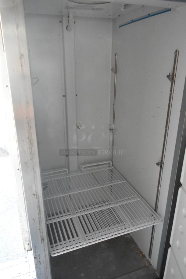 Interior view of a commercial-grade Arctic Air cooler with white wire shelves, part of a fully equipped mobile kitchen trailer.