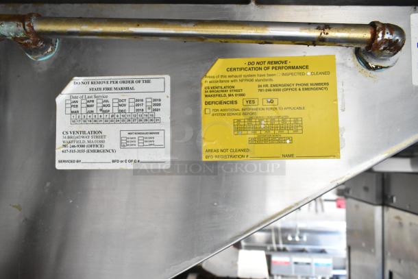 Close-up view of certification labels on a food trailer's exhaust system, including inspection and cleaning dates.