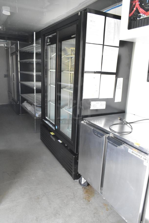 Brand new unbranded food trailer interior with commercial fridge, Beverage-Air cooler, and storage shelves. Ideal for mobile kitchen.
