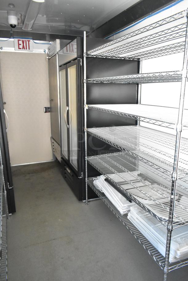 Fully equipped mobile kitchen trailer, featuring commercial-grade appliances, storage racks, and walk-in cooler. Brand new condition.