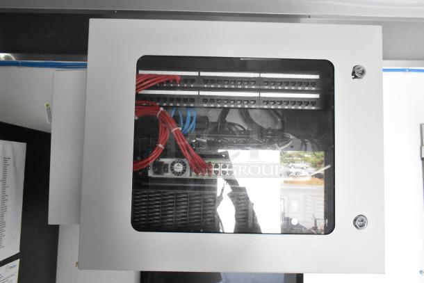 Network equipment cabinet with wiring inside a fully outfitted mobile kitchen trailer. Visible red and blue cables.
