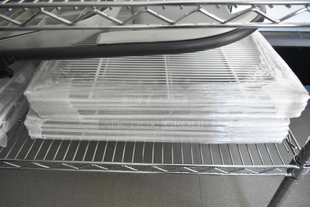 Stacked wire shelving units packed in plastic wrap, part of a fully equipped mobile kitchen trailer.