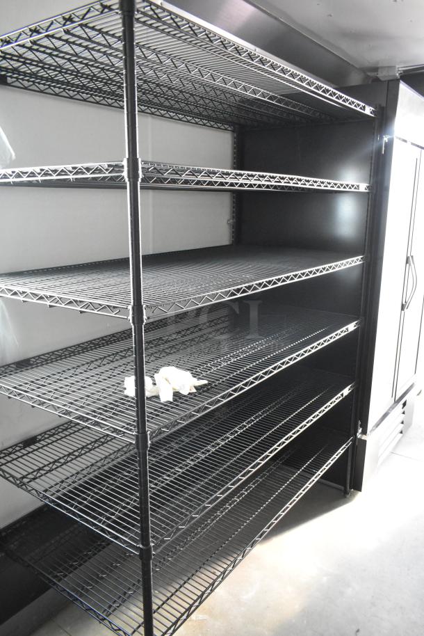 Empty wire shelving in a new, fully outfitted mobile food trailer, ready for use in a commercial kitchen setup.