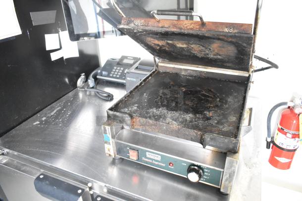 Waring Toasted Supremo Panini Press on stainless steel counter in food trailer with fire extinguisher nearby.