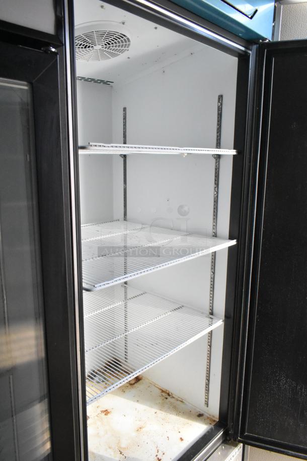 Interior of Beverage Air reach-in cooler with three wire shelves, inside an unbranded food trailer.