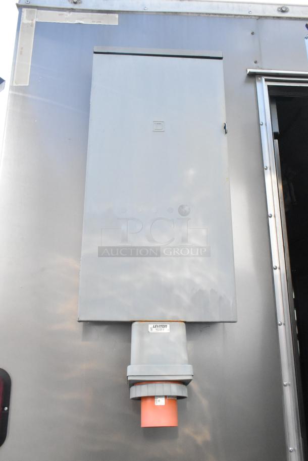Exterior of a fully outfitted unbranded food trailer with a Leviton power outlet and utility panel.