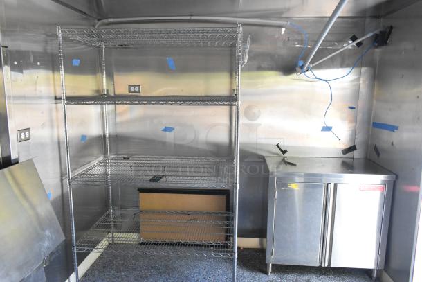 Unbranded food trailer interior with wire shelving, stainless steel storage, and Coleman's Mack Ventilation System visible. Ready to be outfitted.