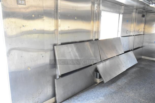 Unbranded food trailer interior, stainless steel panels, Coleman's Mack ventilation, shelves, outlets visible, ready for equipment.