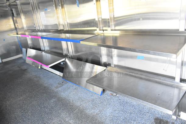 Unbranded food trailer interior with stainless steel shelving, Coleman's Mack ventilation system, ready for kitchen equipment.
