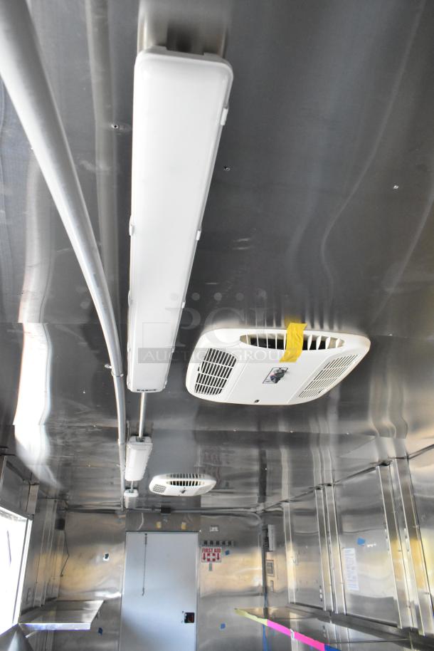 Interior of a brand new food trailer with Coleman's Mack Ventilation System, fluorescent lighting, and metal shelving.
