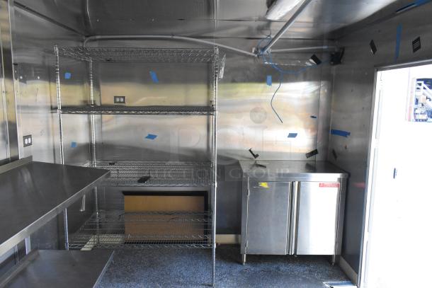 Unbranded food trailer with Coleman's Mack ventilation, wire shelving, and stainless steel surfaces. Ready for outfitting.