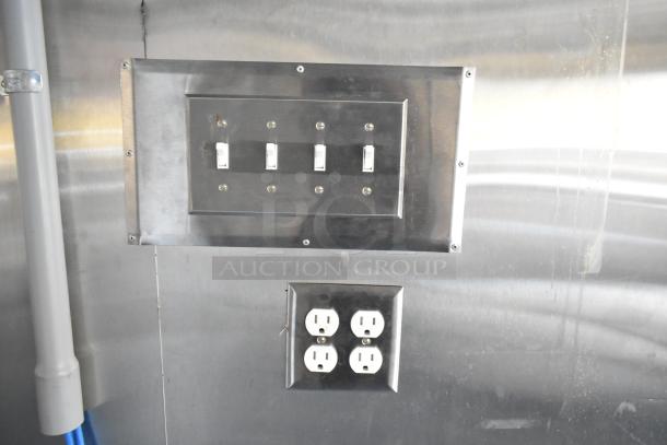 Electrical panel with switches and four outlets inside an unbranded food trailer. Stainless steel finish, ready for equipment installation.